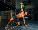 man in black shorts and black tank top doing push up