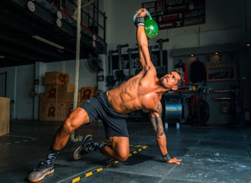 man in black shorts and black tank top doing push up