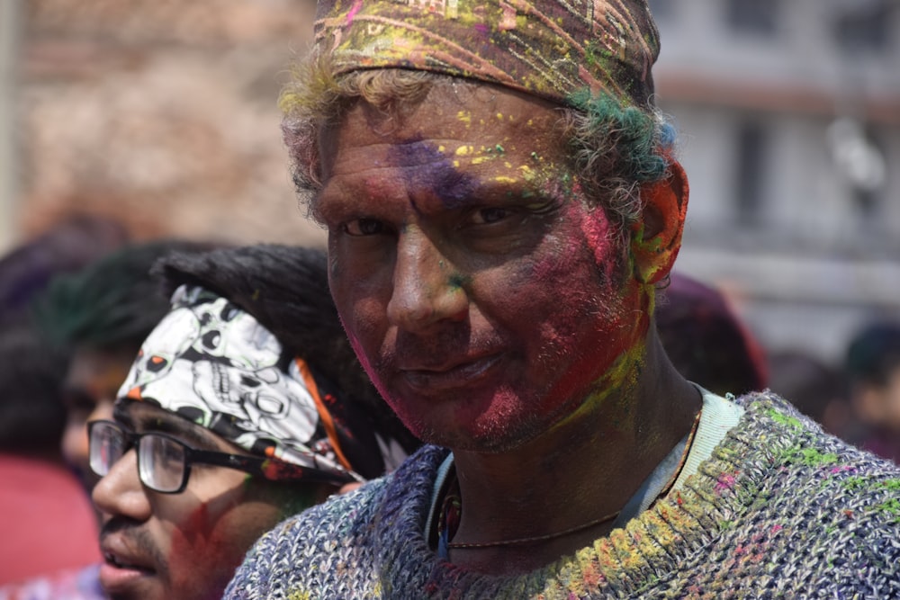 man in black and white shirt with green yellow and red powder on face