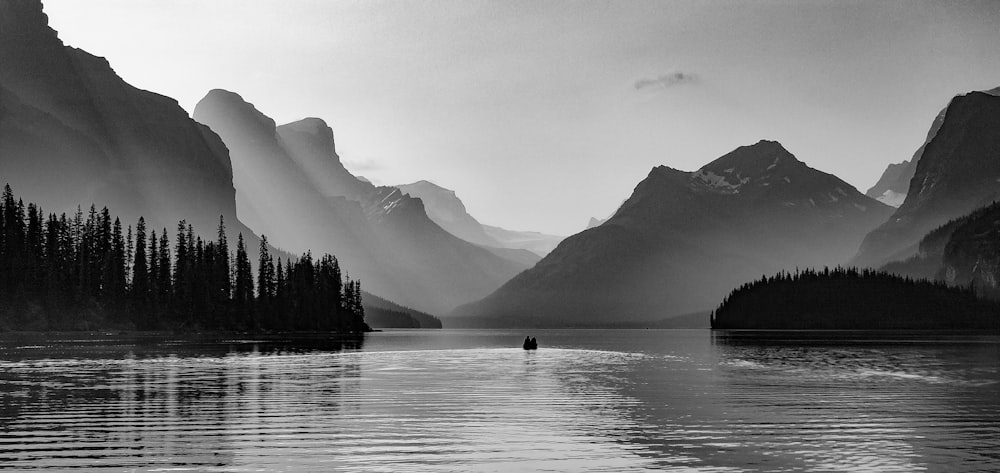 grayscale photo of person riding on boat on lake