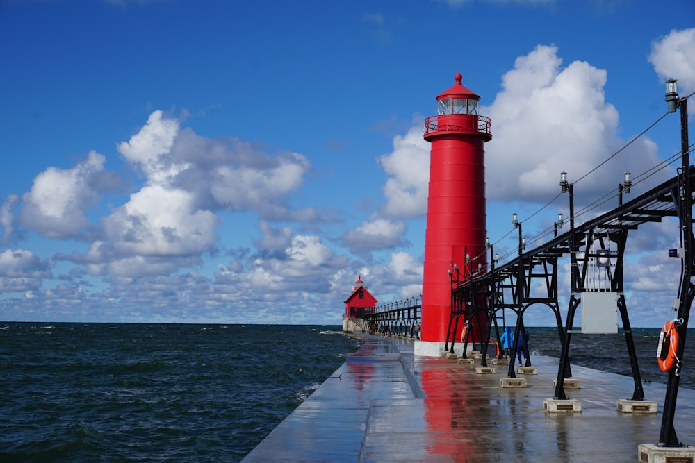 Faro rojo y blanco cerca del cuerpo de agua durante el día