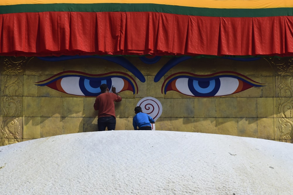 man in brown jacket standing beside blue and red dragon house