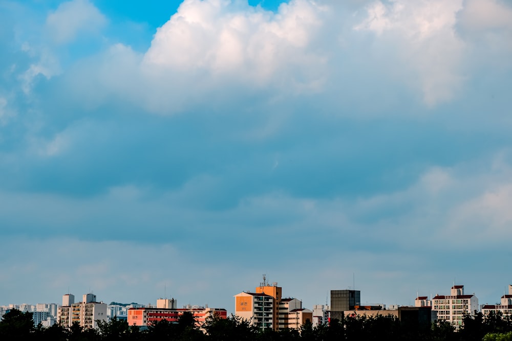 city buildings under white clouds and blue sky during daytime