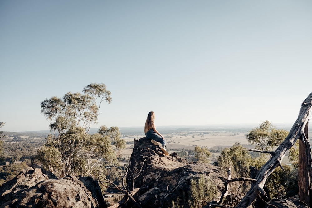 woman sitting on rock formation during daytime