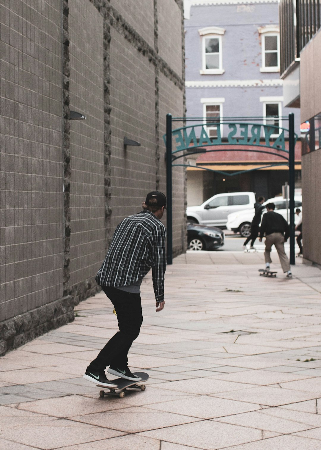 man in black and white stripe shirt walking on sidewalk during daytime