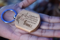 Hands holding a finely engraved wooden keychain with a custom design.