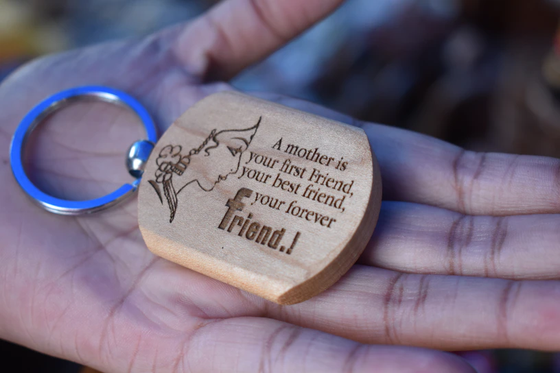 Close-up of a personalized wooden keychain with intricate laser-cut details on a soft beige background.