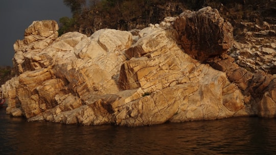 brown rock formation near body of water during daytime in Bhedaghat India