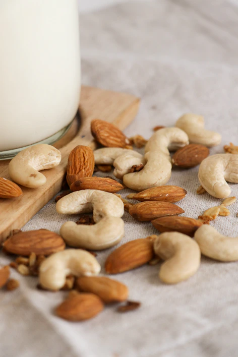 Close-up of assorted premium almonds and cashews in a rustic wooden bowl.