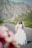 Bride and groom smiling with mountain view background at outdoor wedding venue.