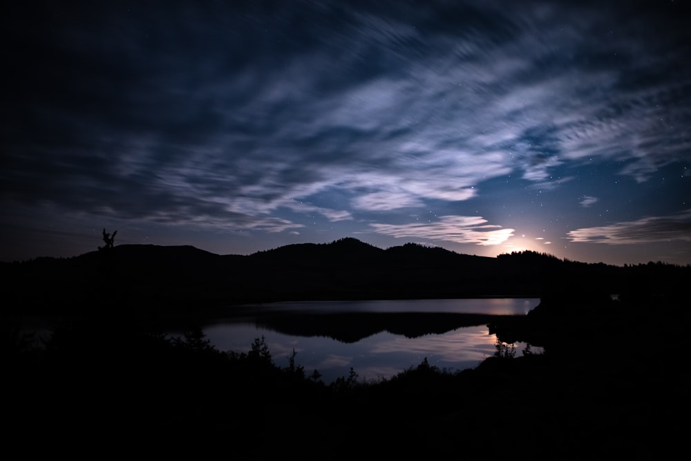 silhouette of mountain near body of water during night time