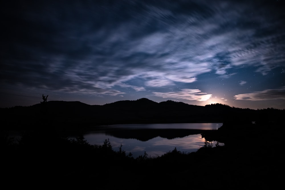 silhouette de montagne près d'un plan d'eau pendant la nuit