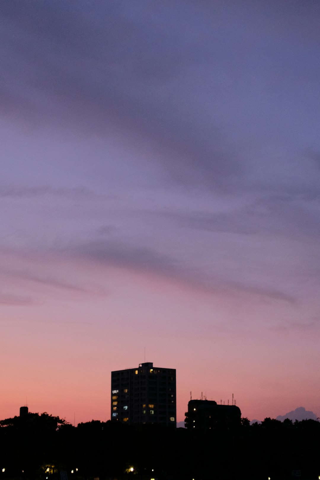 silhouette of city buildings under cloudy sky during sunset