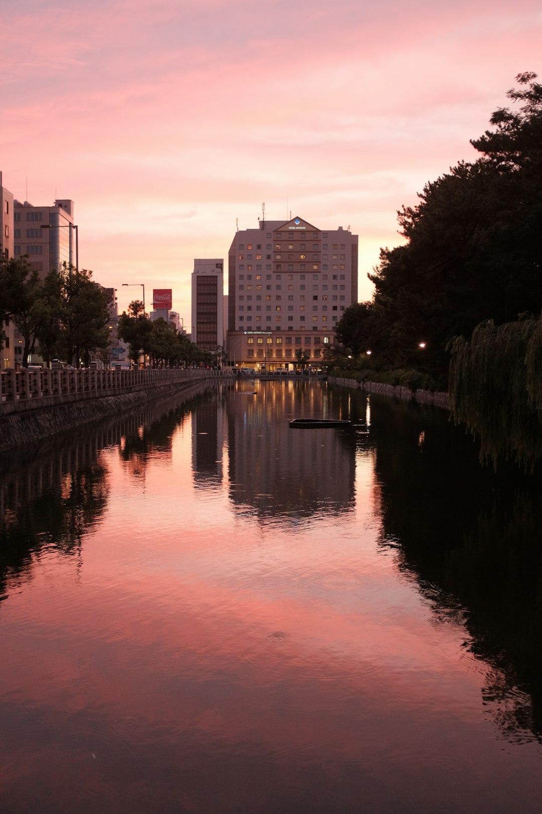 body of water near trees and buildings during sunset