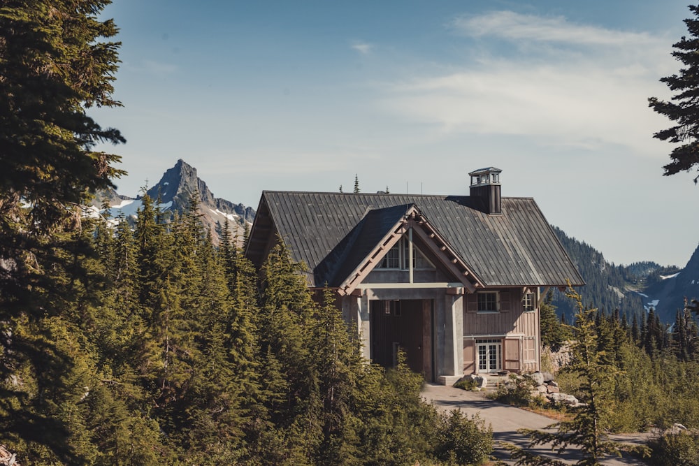 brown and white wooden house near green trees and mountain during daytime