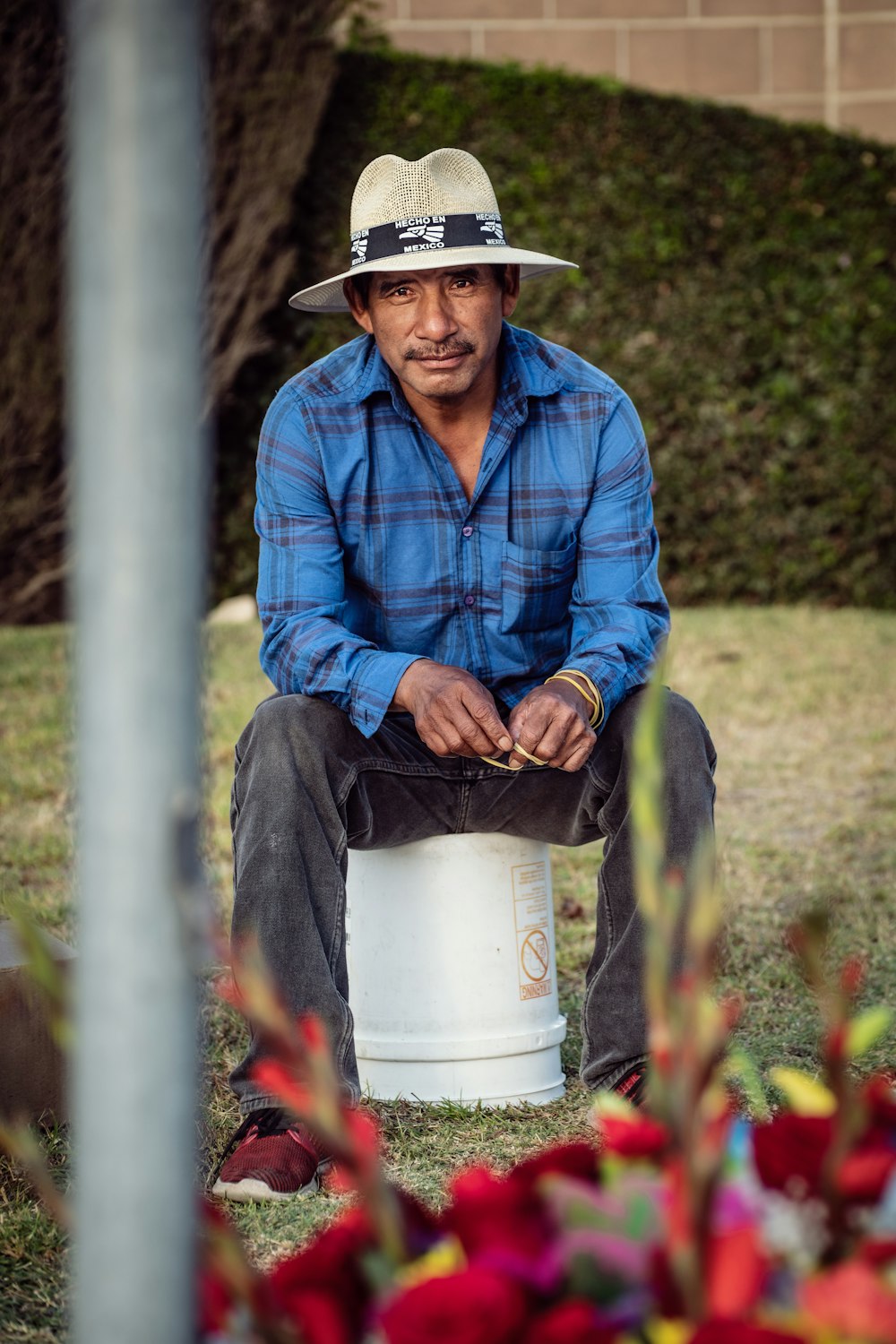 homem na camisa social azul e jeans azul vestindo chapéu branco sentado no plástico branco