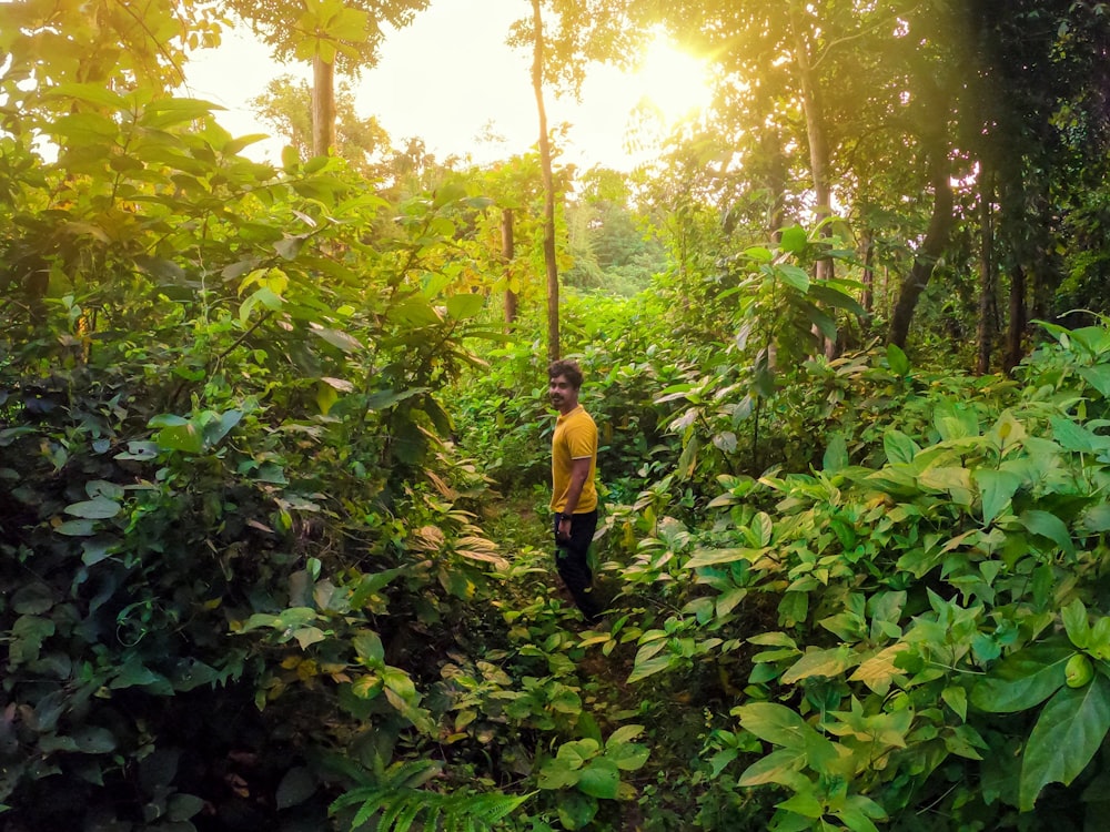 woman in yellow long sleeve shirt and black pants standing on green plants during daytime