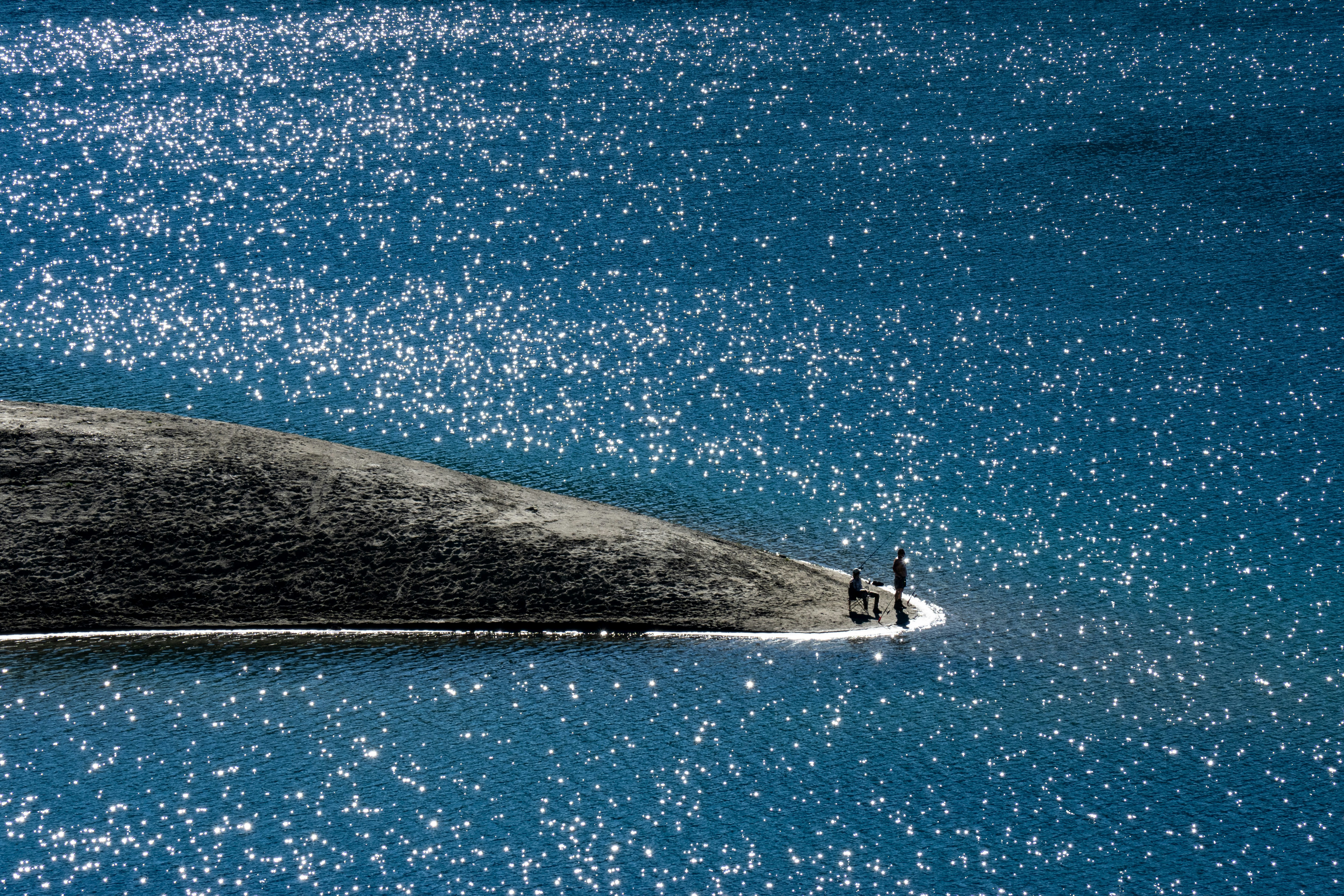 person in white shirt and black pants standing on white surfboard on blue sea during daytime