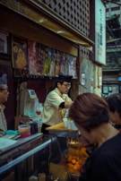 A cheerful vendor serving customers at a busy food stall.