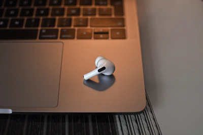 A stylish kytrexx wireless earbud set resting on a polished wooden desk beside a laptop.