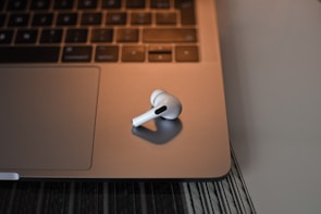 Wireless headphones resting on a modern desk beside a laptop.