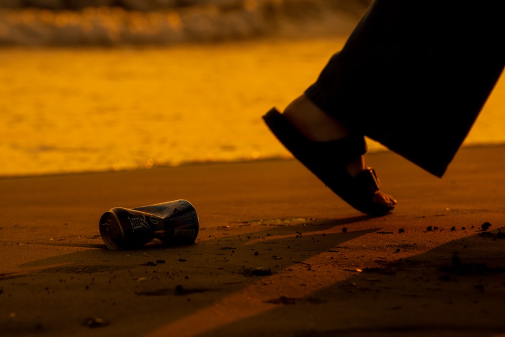 person in black pants wearing black and white shoes standing on brown sand during daytime