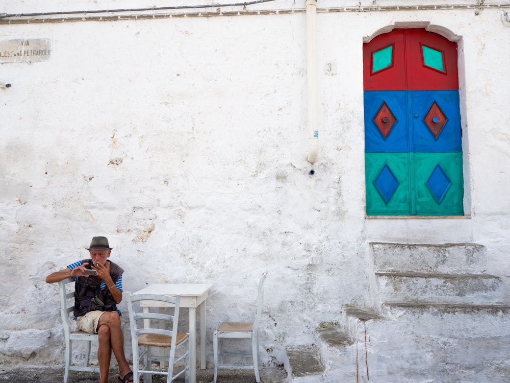 man in black jacket sitting on white plastic chair