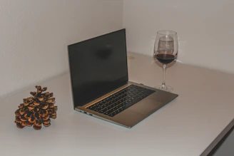 Elegant office desk with laptop displaying customs data and wine bottles in the background.