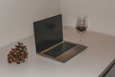 A clean office desk with wine and nude color accents, featuring a laptop and notebooks.