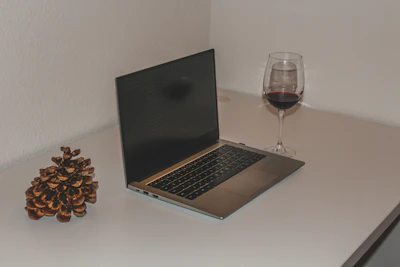 Elegant office desk with laptop displaying customs data and wine bottles in the background.