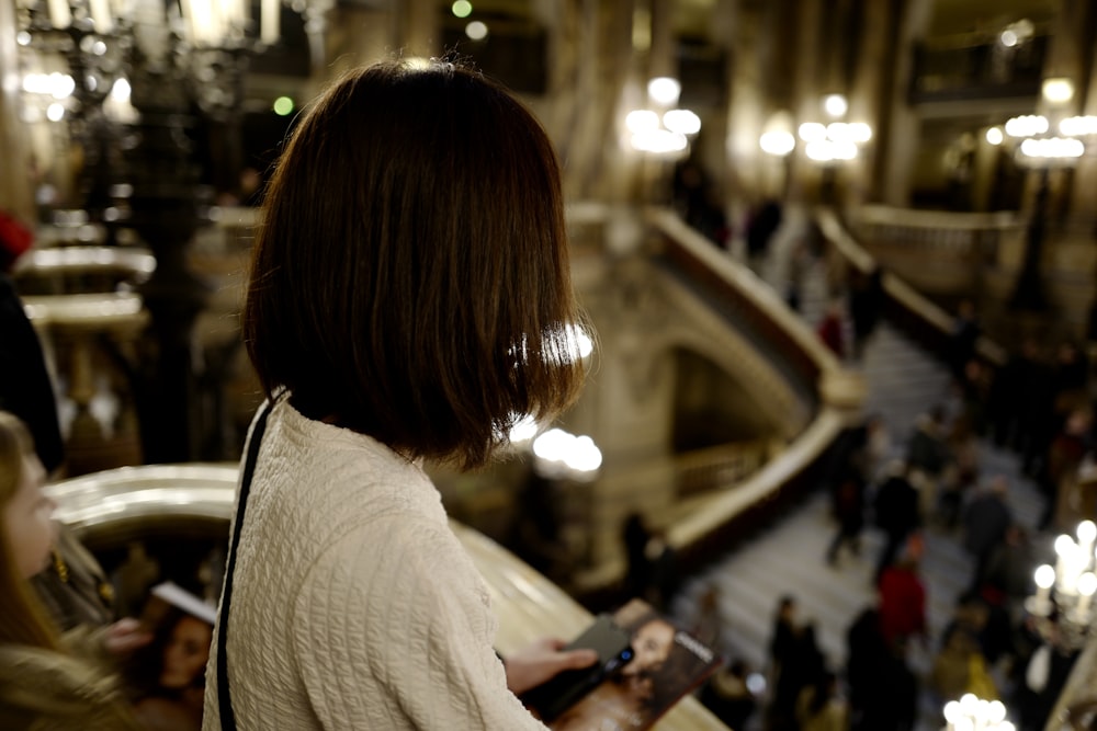 woman in white shirt holding smartphone