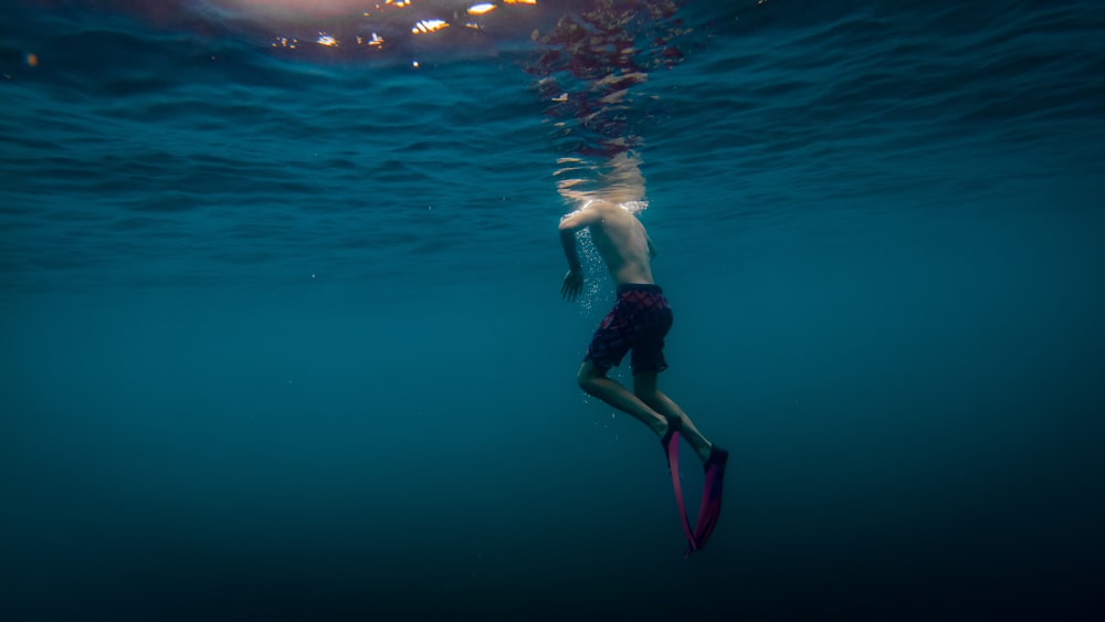 man in black shorts swimming in water