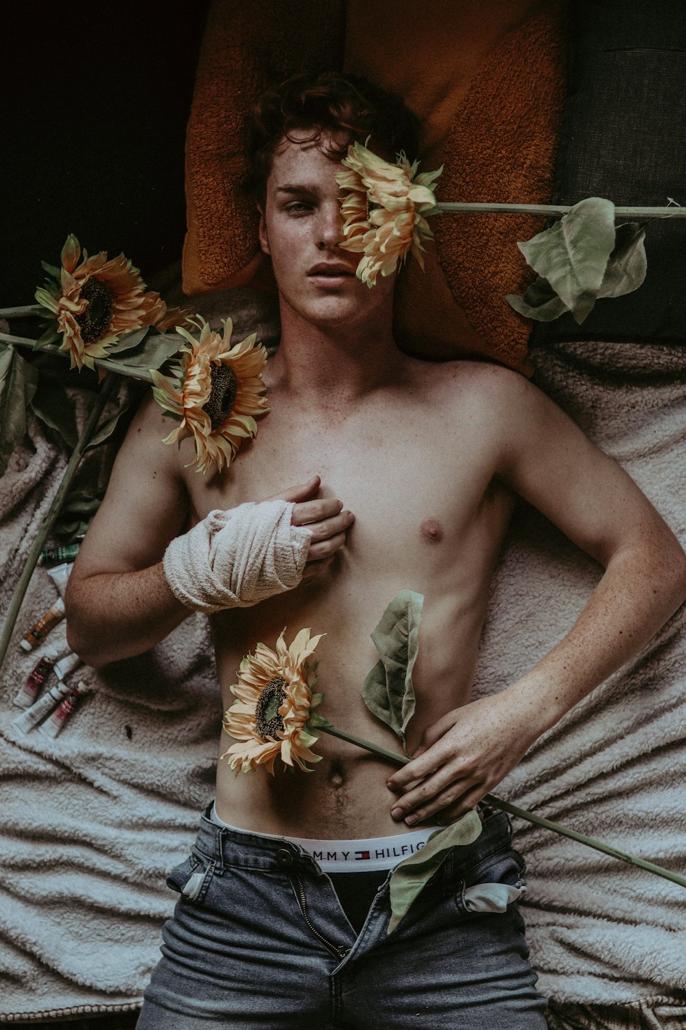 uomo in topless con copricapo floreale oro e verde