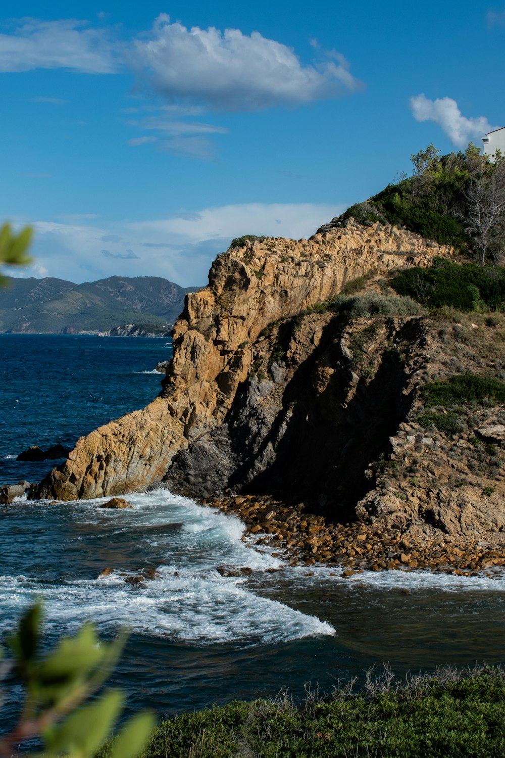 brown rocky mountain beside sea during daytime