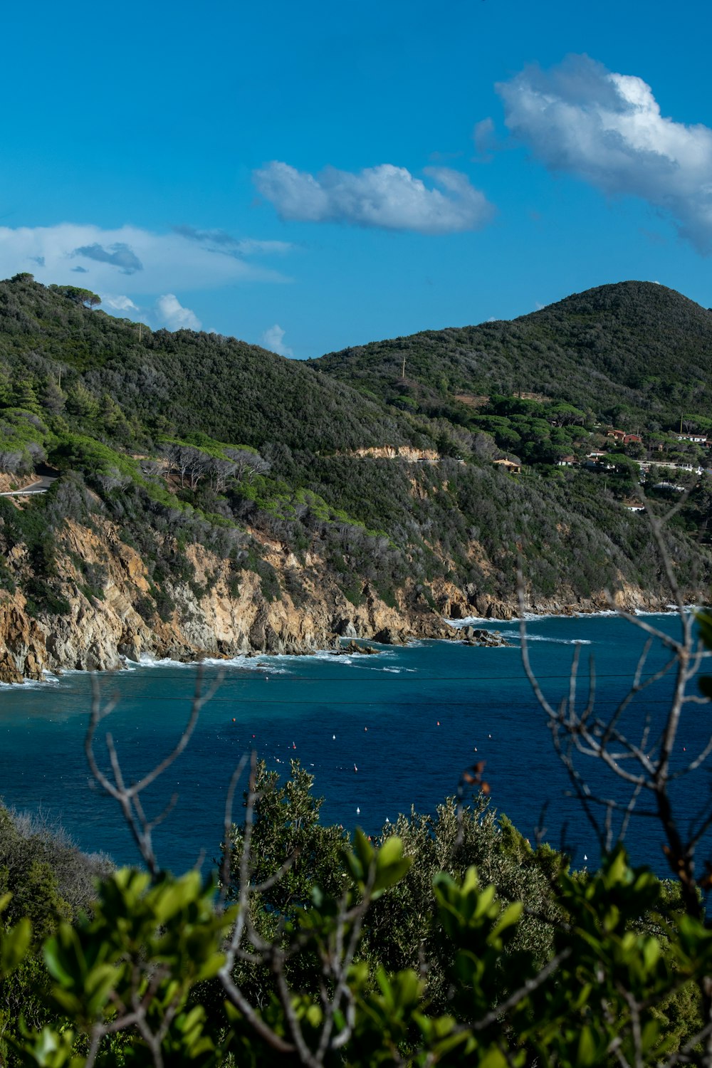 green and brown mountain beside blue sea under blue sky during daytime