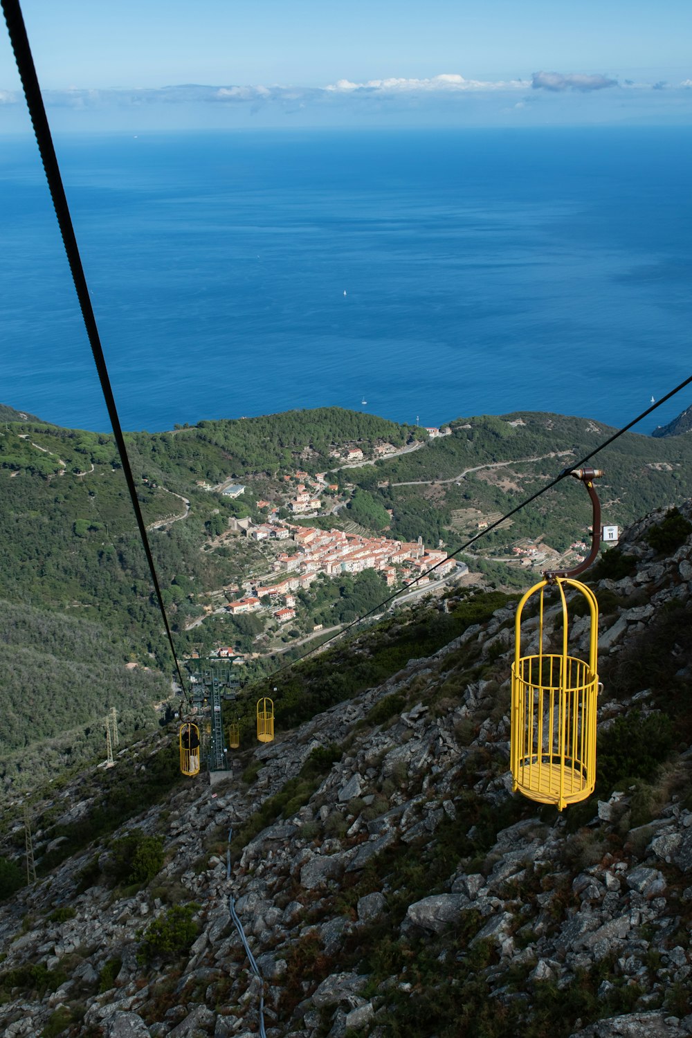 Teleférico amarillo sobre árboles verdes y montañas durante el día