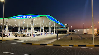 Modern gas station exterior at sunset with sleek cars and clean surroundings.
