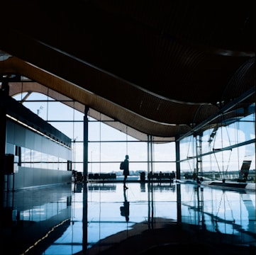 Traveler wearing a premium leather backpack walking through an airport terminal with natural light.