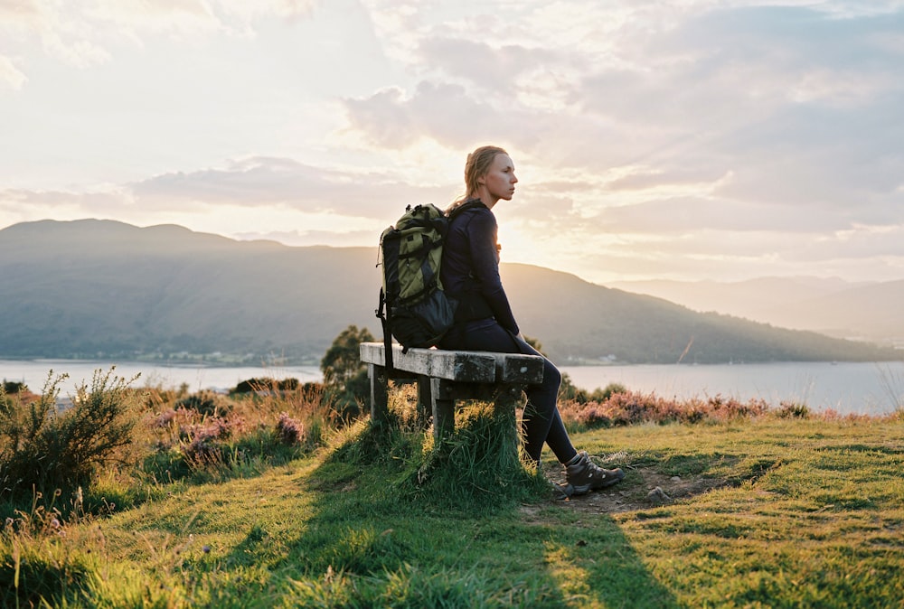 man in black jacket sitting on brown wooden bench during daytime