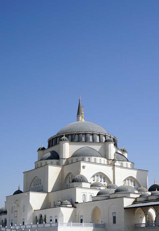 white and brown concrete building under blue sky during daytime in Sharjah Mosque United Arab Emirates