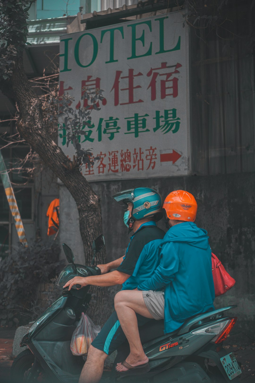 man in red t-shirt and orange helmet sitting on motorcycle
