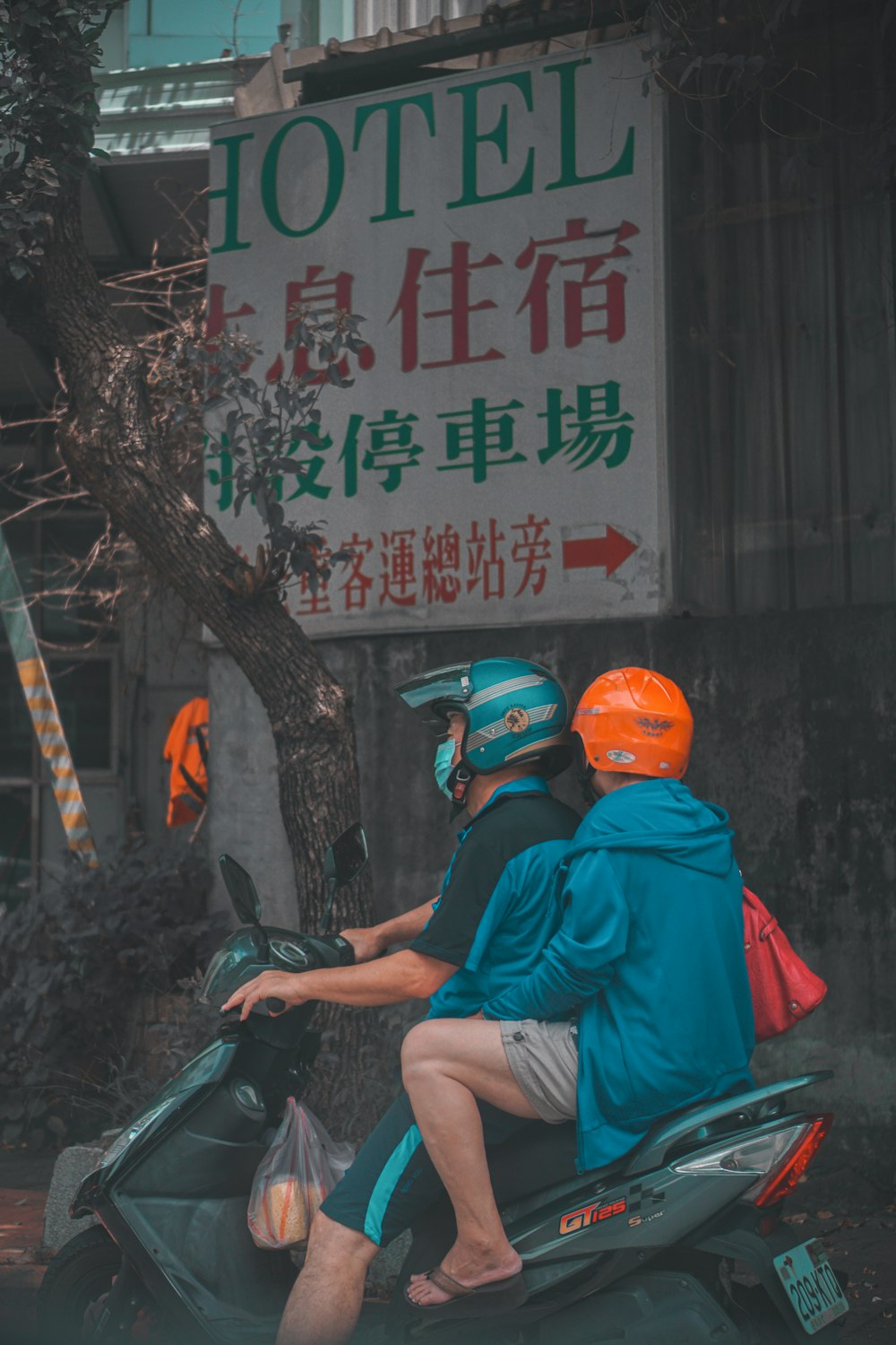 Homme en t-shirt rouge et casque orange assis sur une moto