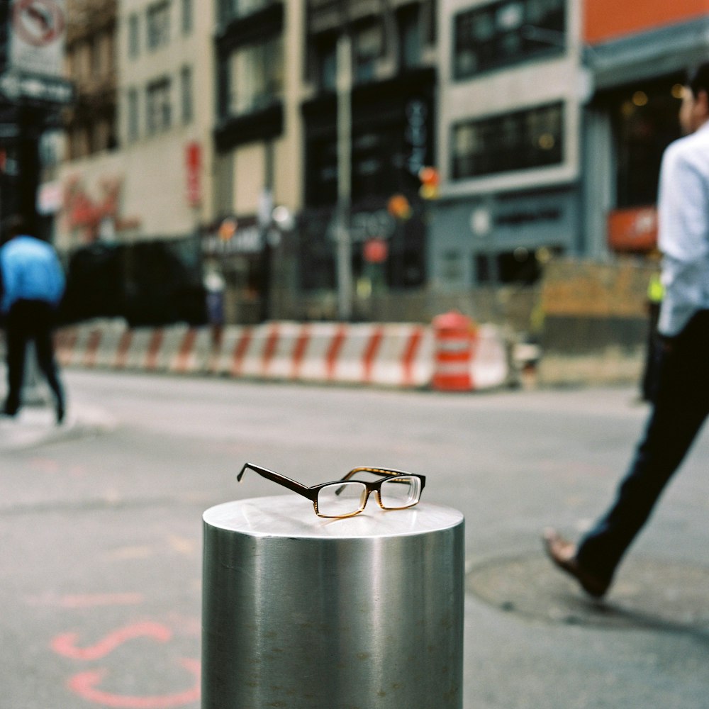 black framed eyeglasses on gray metal round container