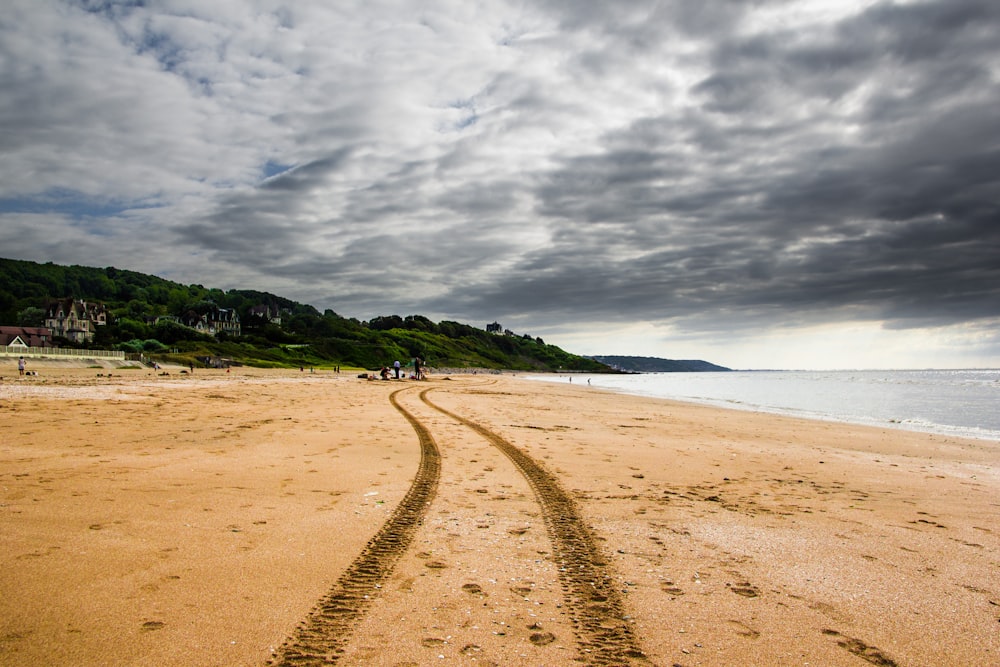 brown sand near body of water under cloudy sky during daytime