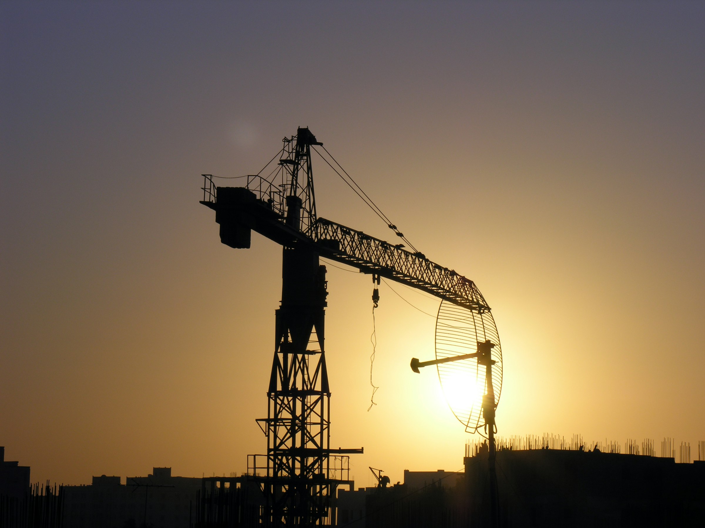 Une grue à tour se découpant sur le soleil du soir