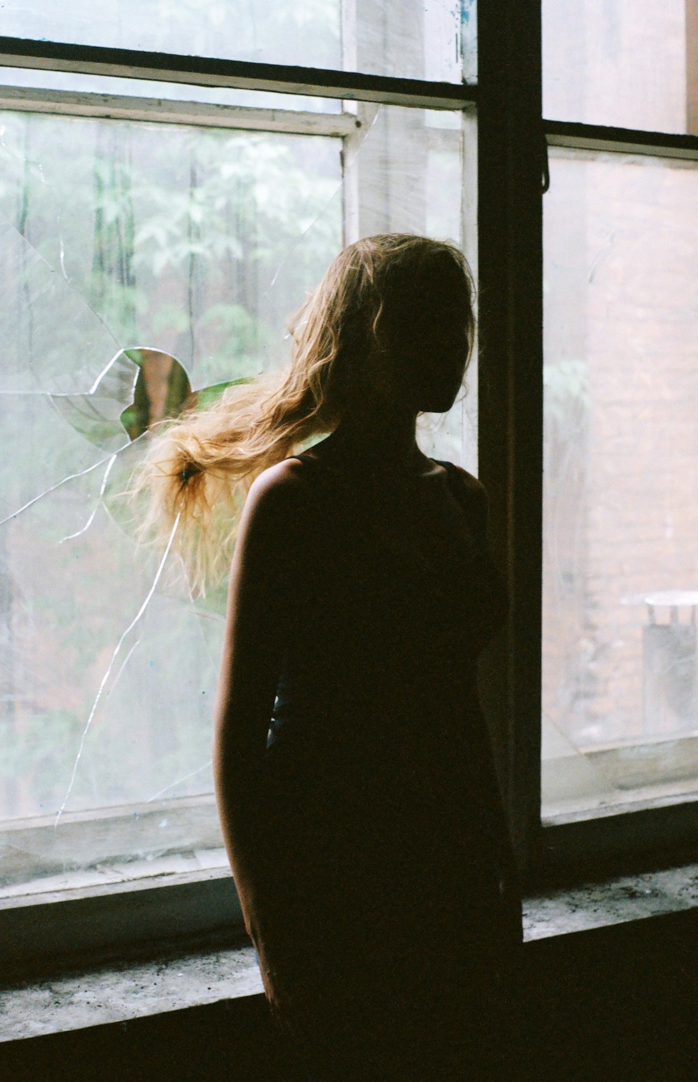 woman in black tank top standing beside window