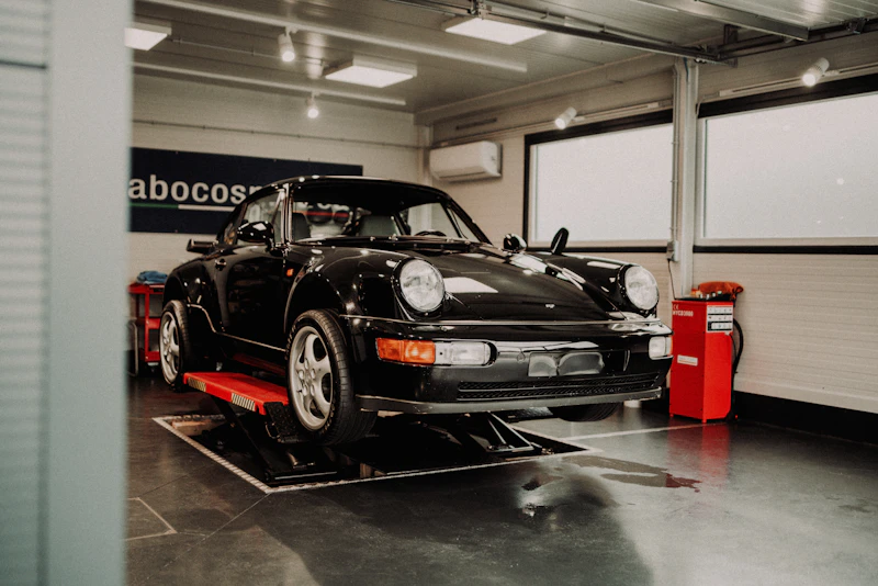Black Porsche 911 up on the lift, delivery ready