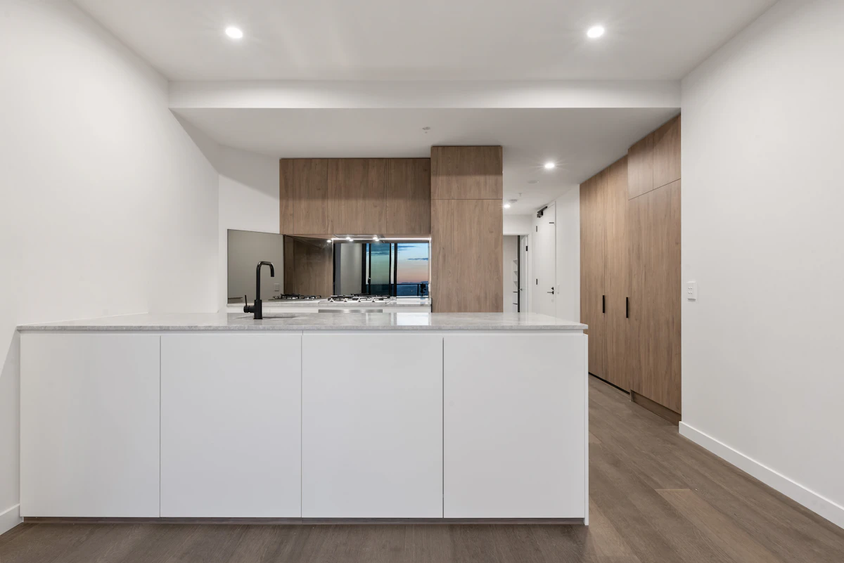 Cuisine spacieuse avec plan de travail blanc et meubles en bois fraîchement installés