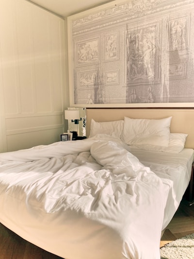 A serene bedroom environment showcasing an unmade bed with a suitcase beside it.
