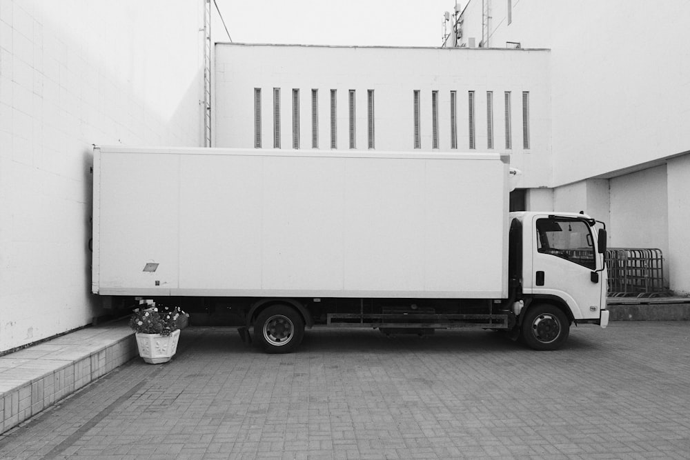 Camion blanc garé près d’un bâtiment blanc